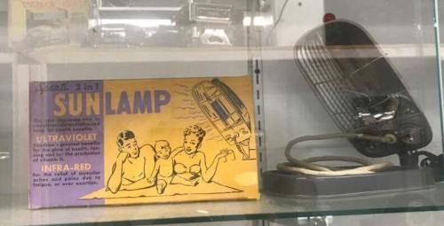 A vintage 2-in-1 sun lamp box with illustrations of people using it, displayed next to the actual lamp.