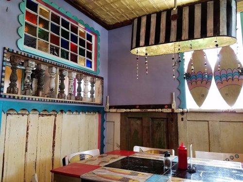 Colorful restaurant interior featuring unique decor, stained glass windows, and a vibrant table setting.