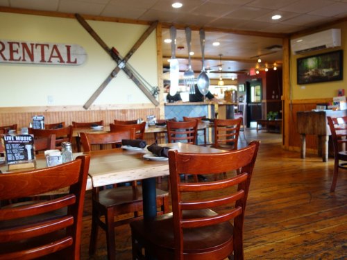 Cozy restaurant interior with wooden tables and chairs, ski decor, and a warm, inviting atmosphere.