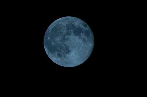 A close-up view of a full moon against a black night sky, showcasing its craters and surface details.