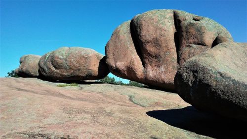Large, rounded boulders balanced on a rocky surface under a clear blue sky.