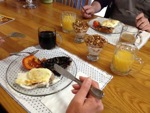 A breakfast table with plates of eggs, toast, fruit, yogurt parfaits, and drinks, including coffee and orange juice.