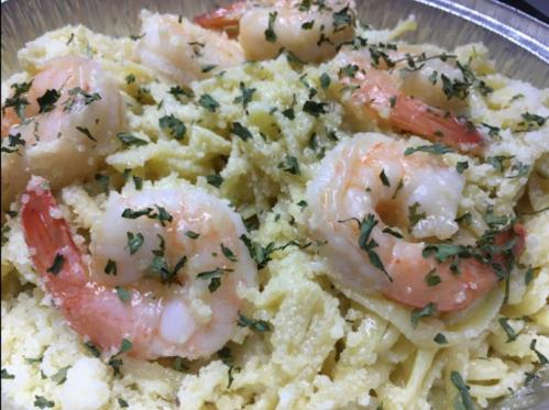A close-up of shrimp pasta topped with parsley in a silver tray.