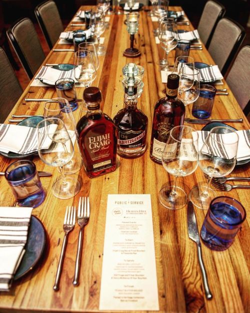 A beautifully set dining table with whiskey bottles, glasses, and a menu, ready for a gathering.