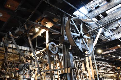A vintage workshop with large, intricate machinery and pulleys, showcasing a blend of wood and metal elements.
