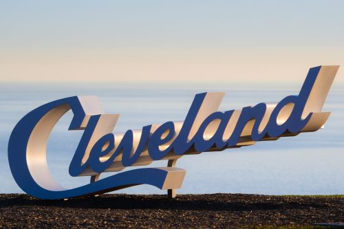 A large, stylized sign reading "Cleveland" against a serene lake backdrop.