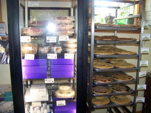 A display case filled with various baked goods, including pies and desserts, in a cozy bakery setting.