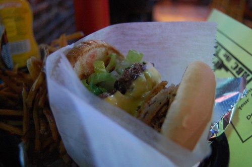 A close-up of a burger with lettuce and cheese, served with a side of fries in a casual dining setting.