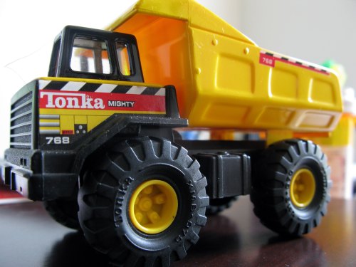 A close-up of a Tonka toy dump truck in black and yellow, featuring large wheels and a detailed design.