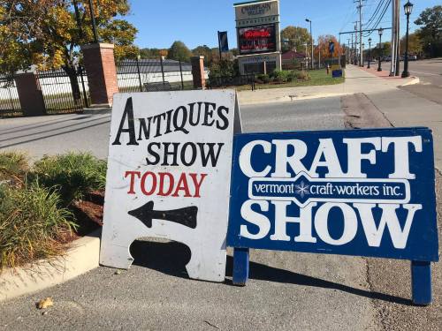 Two signs on a sidewalk: one for an "Antiques Show Today" with an arrow, and another for a "Craft Show."