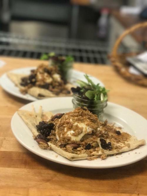 Two plates of food featuring flatbreads topped with yogurt, granola, and blackberries, served with a side salad.