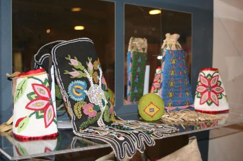 Colorful traditional beaded crafts displayed on a shelf, featuring intricate floral designs and vibrant patterns.