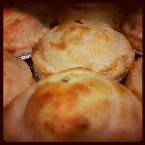 A close-up of golden-brown baked pies, showcasing their flaky crusts and round shapes.