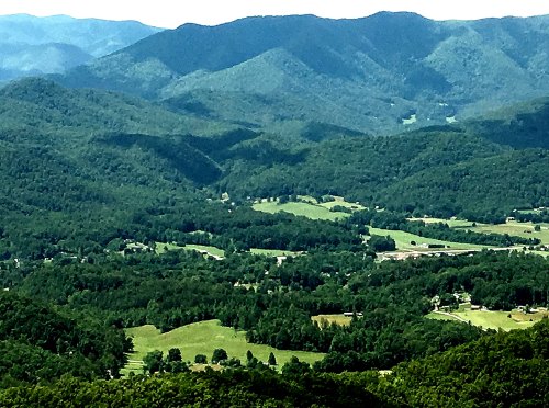 A panoramic view of lush green mountains and valleys under a clear blue sky.