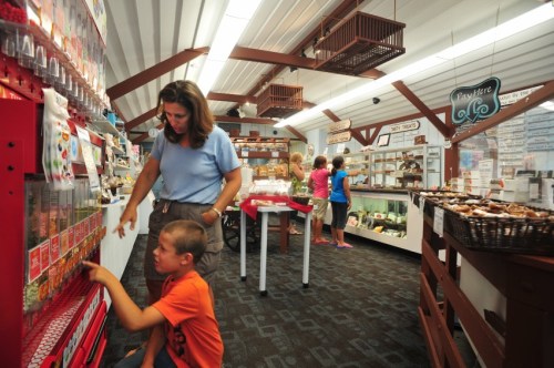 A woman helps a boy at a vending machine in a shop, while other customers browse nearby.