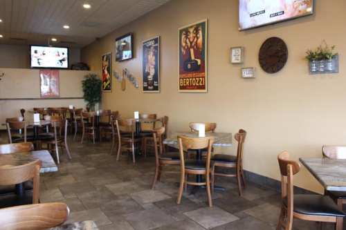 A cozy restaurant interior with wooden tables, chairs, and vintage posters on the walls.