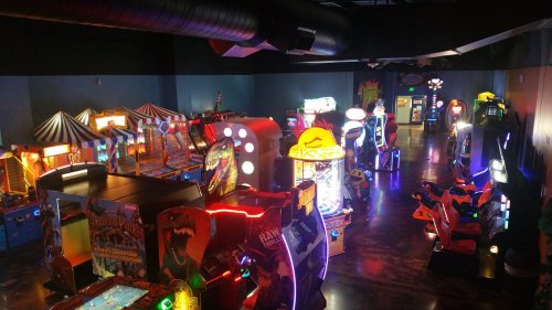 A vibrant arcade filled with various colorful games and machines, illuminated by neon lights.