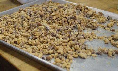 A baking tray filled with a mixture of roasted and salted peanuts scattered across the surface.