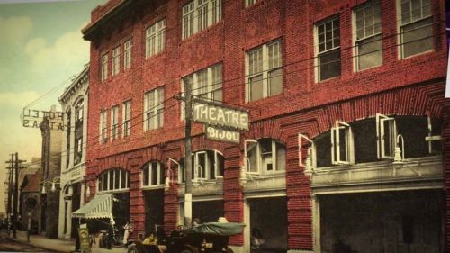 Historic street view featuring the Bijou Theatre and Hotel, with vintage cars and brick architecture.
