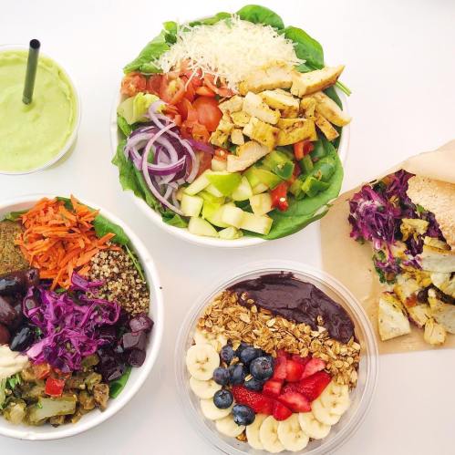 A colorful spread of healthy bowls: salad with chicken, quinoa bowl, and an acai bowl topped with fruits and granola.