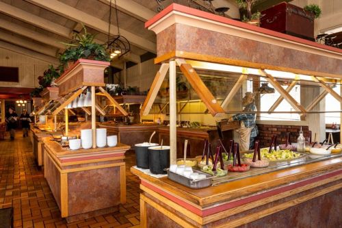 A spacious restaurant buffet with various food stations, including salads and toppings, in a warm, inviting setting.