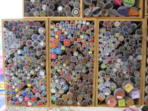 A collection of colorful buttons organized in wooden storage boxes, showcasing various shapes and designs.