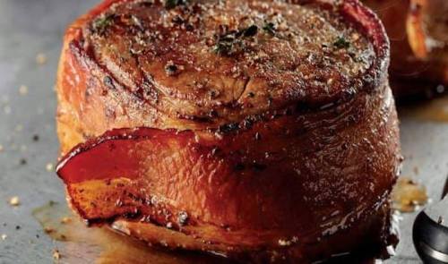 A perfectly cooked beef filet mignon wrapped in bacon, seasoned and glistening with juices.