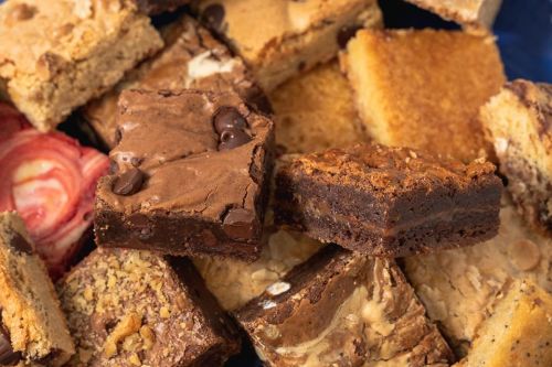 A variety of delicious brownies and blondies stacked together, showcasing different textures and toppings.