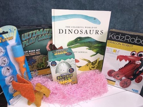 A collection of dinosaur-themed toys and books, including a play set, a book, a dino egg, and a robot kit.