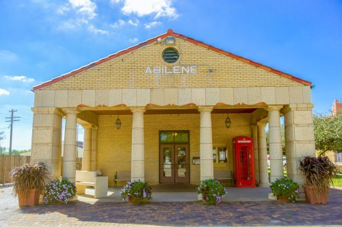 Historic building in Abilene with columns, a red phone booth, and flower pots under a clear blue sky.