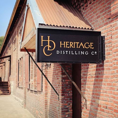 Sign for Heritage Distilling Co. on a brick building with a sloped roof.
