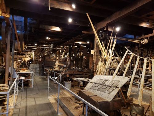 A historic workshop filled with vintage machinery, tools, and wooden beams, showcasing a rich industrial heritage.