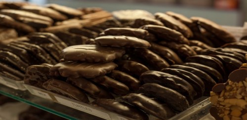 A display of assorted chocolate-covered cookies and treats stacked neatly on a glass shelf.
