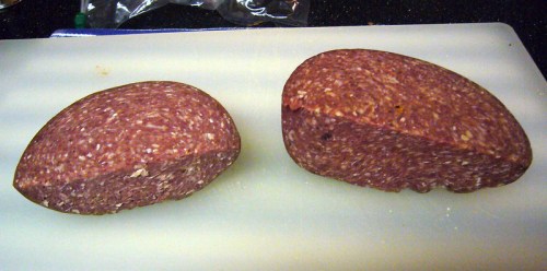 Two pieces of sliced meatloaf on a cutting board, showcasing a textured, pinkish interior.