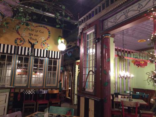 Colorful restaurant interior with whimsical decor, featuring painted walls, unique lighting, and eclectic furniture.