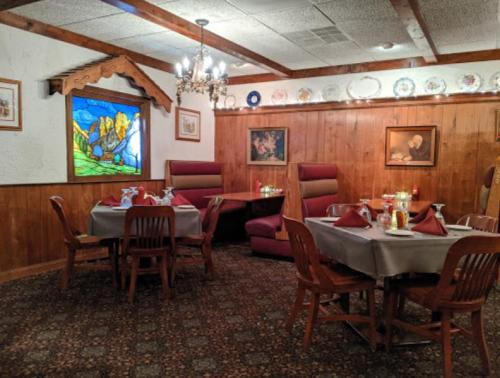 Cozy restaurant interior with wooden walls, tables set for dining, and a colorful stained glass window.