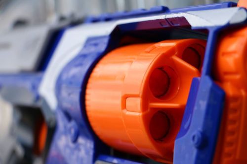 Close-up of a toy blaster with an orange drum and blue casing, showcasing its colorful design and details.