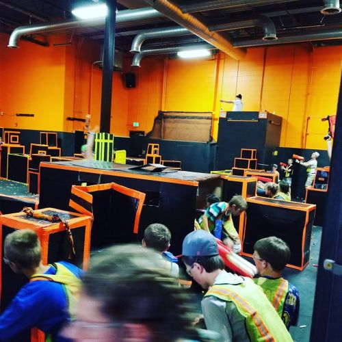 A vibrant indoor trampoline park with kids playing and jumping on colorful structures and obstacles.
