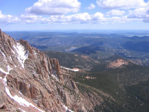 A panoramic view of rugged mountains and valleys under a partly cloudy sky, showcasing natural beauty and vast landscapes.
