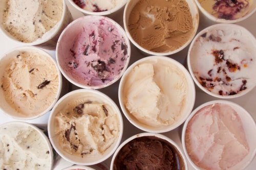 A variety of ice cream flavors in cups, including chocolate, vanilla, strawberry, and more, arranged closely together.