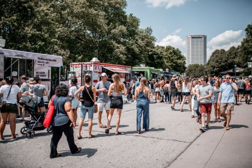 A bustling food truck festival with crowds enjoying various food options under a sunny sky.