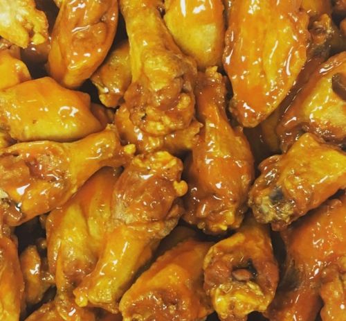 A close-up of golden-brown chicken wings coated in a shiny, spicy sauce.