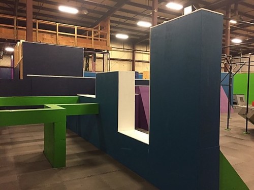 Colorful indoor obstacle course with various geometric structures in blue, green, and purple.