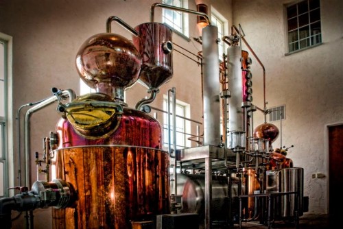 A copper distillation apparatus with pipes and tanks, set in a well-lit industrial space.