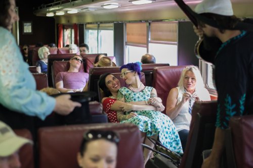 A lively train interior with diverse passengers, some chatting and others relaxing, creating a vibrant atmosphere.