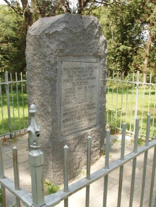 A stone memorial surrounded by a fence, honoring the children of Phoebe Ann Jensen Weisman, with names and ages inscribed.