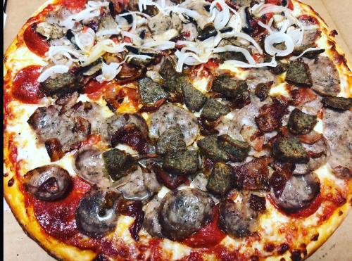 A pizza topped with pepperoni, sausage, onions, and various meats on a golden crust.