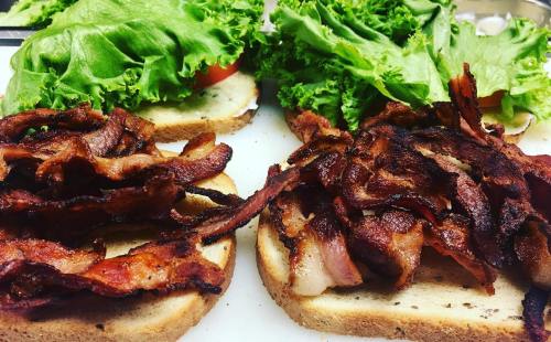 Two slices of bread topped with crispy bacon, lettuce, and tomato, ready to be assembled into a sandwich.