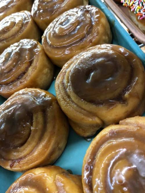 Freshly baked cinnamon rolls with a glossy caramel glaze, arranged neatly on a blue platter.
