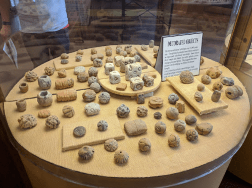Display of various decorated clay objects in a glass case, showcasing intricate designs and shapes.